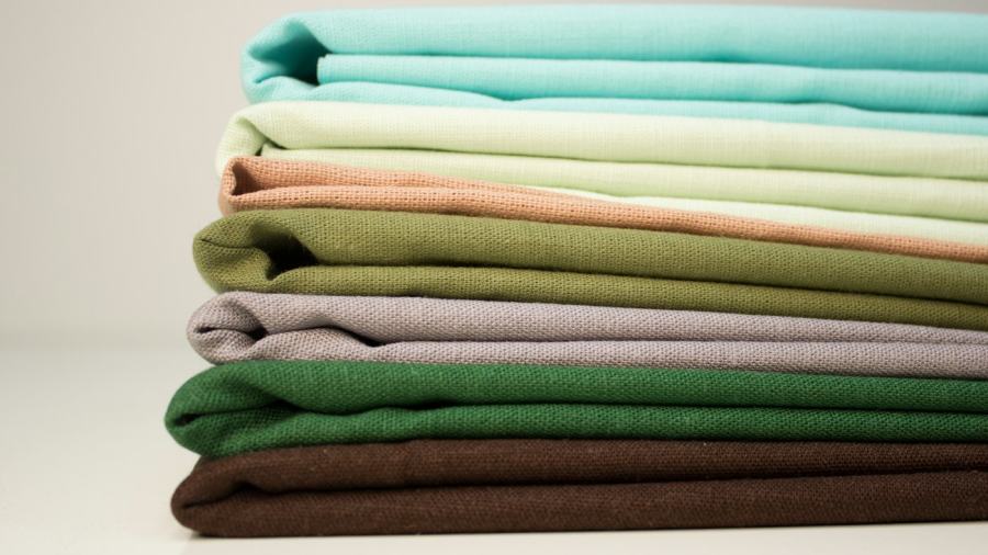 Stack of folded cotton home textiles in several colours