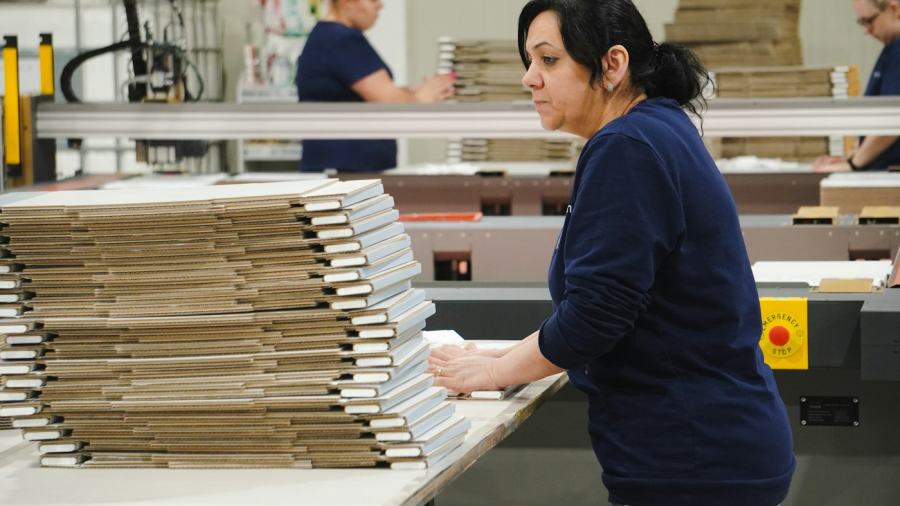 Worker handling flat cartons on a packaging line